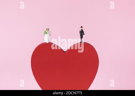 A closeup shot of bride and groom figurines standing on red heart Stock Photo
