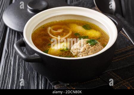 Homemade Austrian rindsuppe based on beef broth with dumplings close-up in a saucepan on the table. horizontal Stock Photo