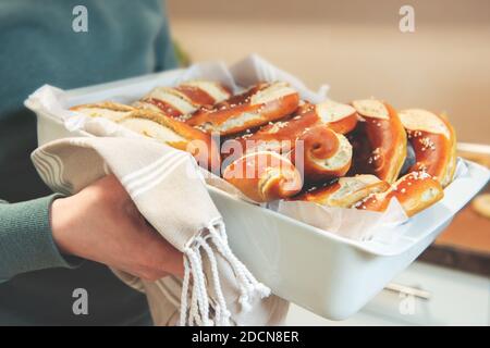 Closeup of male hands holding freshly baked pretzel in bakery Stock Photo