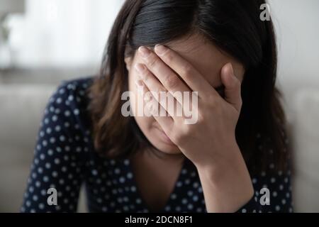 Close up frustrated depressed Asian woman covering face with hand Stock Photo