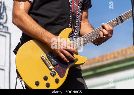An unidentified musician plays an electric guitar during a concert in bright sunlight Stock Photo