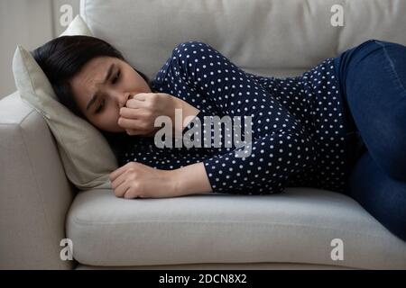 Unhappy depressed Asian young woman lying on couch alone, crying Stock Photo