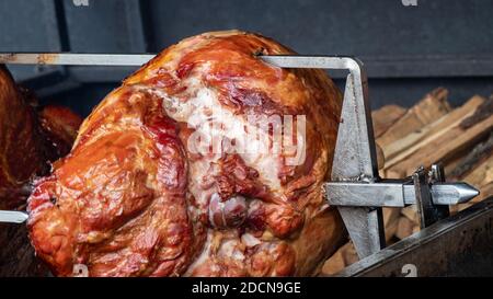 Traditional Veprevo knee (pork knuckle) being cooked on a spit roast in a barbecue in Prague, Czech Republic Stock Photo