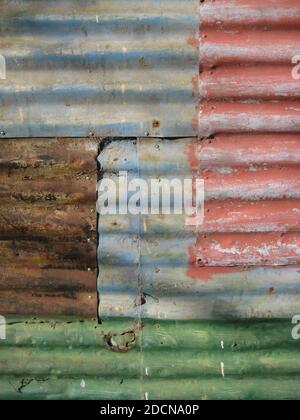 wall made out of corrugated metal sheets with different faded colors and rust, textured background Stock Photo