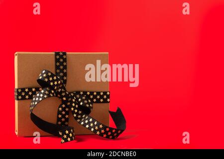 Christmas Gift box or present box with black golden ribbon on red background Stock Photo