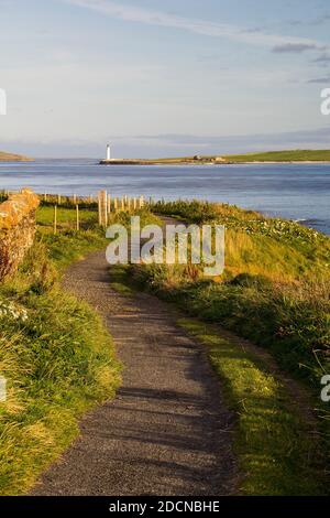 Footpath along Orkney shore with lighthouse on sunny summer day Stock Photo