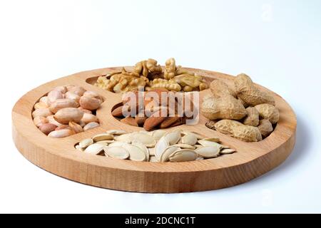 Mix of raw dried nuts on wooden plate isolated on white. Stock Photo