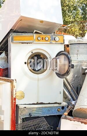 Broken scrap appliances outdoors on the junkyard. Retro obsolete washing machine Stock Photo