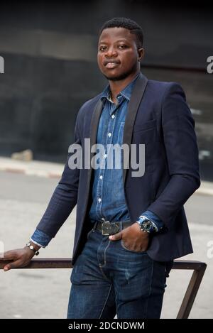 young african man standing in jacket staring smiling. Stock Photo