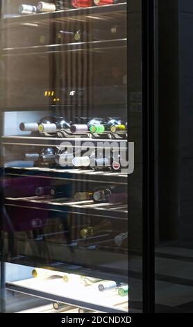 Kitchen wine cooler with shelves full of botttles. Storing bottles of wine in fridge. Stock Photo