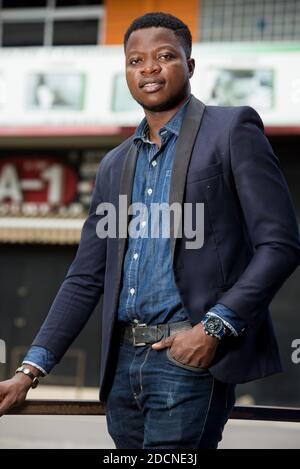 young african man standing in jacket staring smiling. Stock Photo