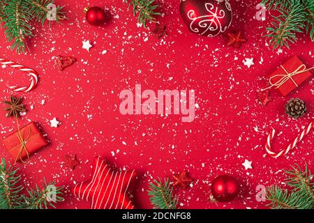 Christmas composition. Frame made of gifts, fir tree, candy, decorations on red background. Christmas, winter, new year concept. Flat lay, top view wi Stock Photo