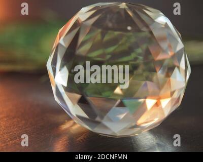 Faceted Glass Orb with multi Light refraction against peacock feather Stock Photo