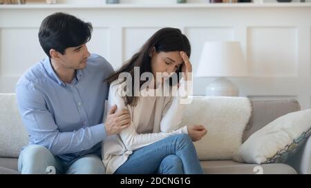 Caring young man hugging suffering woman shoulders supporting in grief Stock Photo