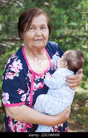Elderly woman carrying a baby in arms, great grandmother portrait with her great grandchild, portrait Stock Photo