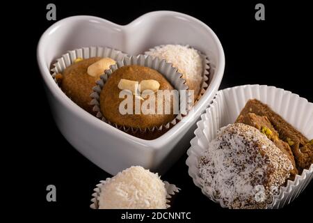 Indian homemade cookies in a heart shaped bowl isolated on black. Stock Photo