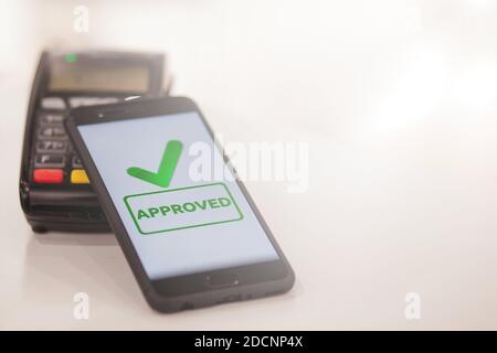 POS terminal, Payment Machine with mobile phone on store background. Contactless payment with NFC technology. Stock Photo
