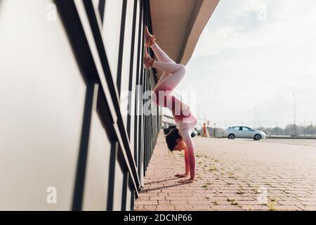 Athetic girl doing handstand against the wall on the street Stock Photo