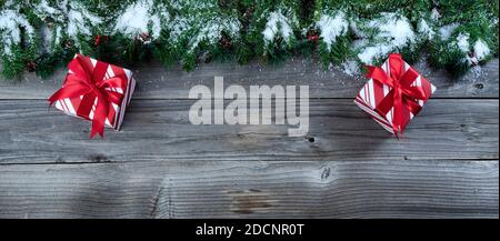 Merry Christmas concept on rustic natural wooden background with snow covered Fir branches plus wrapped giftboxes Stock Photo