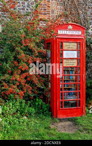 Traditional old red BT telephone box converted into a lending library in a Norfolk village. Stock Photo