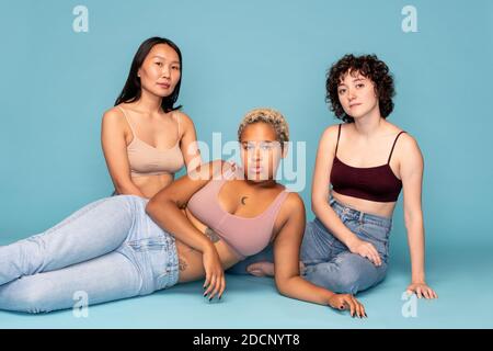 Three contemporary restful girls of Asian, Caucasian and African ethnicities Stock Photo