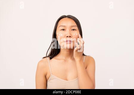Korean or Chinese girl with dark long hair having undereye mask in isolation Stock Photo