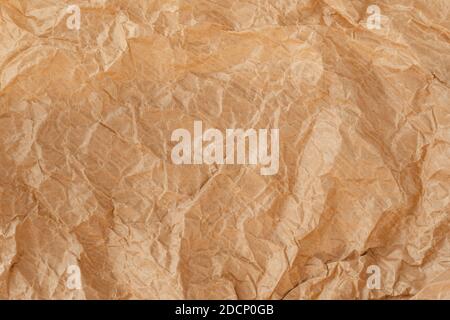 Crinkled wrap sheet, recycle grunge texture sample. Closeup of parchment canvas. Wrapping paper material. Kraft texture. Brown crumpled surface. Stock Photo