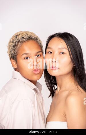 Faces of girls of African and Asian ethnicities standing close to one another Stock Photo