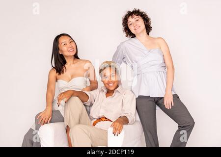 Happy young African woman in casualwear sitting between intercultural friends Stock Photo