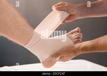 Hands of clinician wrapping foot and leg of patient with flexible ...