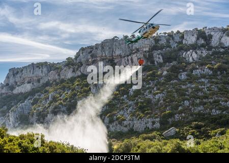 Bomberos (firefighters) putting out a fire in Canuto De La Utrera, using a water bucket on a helicopter Stock Photo