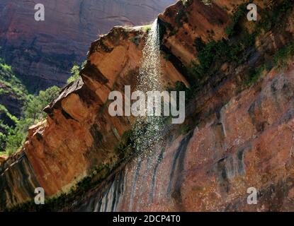 Bottom Up View To A Trickle Of Water From The Lower Emerald Pools At Zion National Park On A Sunny Summer Day With A Clear Blue Sky And A Few Clouds Stock Photo