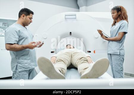 Young African nurse or assistant in uniform looking at doctor during work Stock Photo