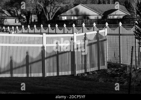 Black & white view of white vinyl picket style fence and shadows; Salida; Colorado; USA Stock Photo