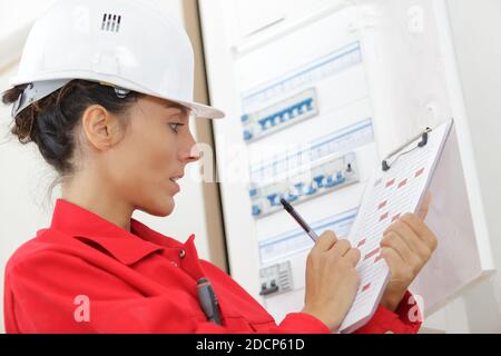 a woman inspecting a fuse board Stock Photo