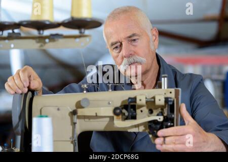 man sews on a singer sewing machine Stock Photo