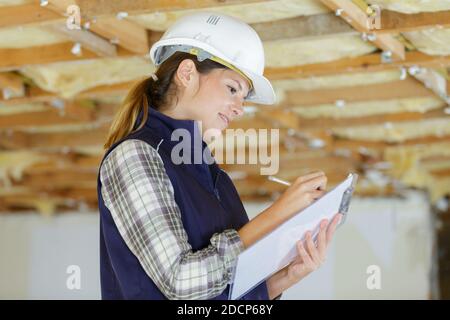 female builder in renovation property writing on clipboard Stock Photo