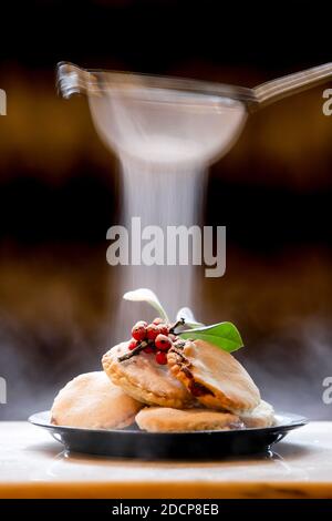 Homemade mince pies decorated with a sprig of holly and given a light dusting of icing sugar. Stock Photo