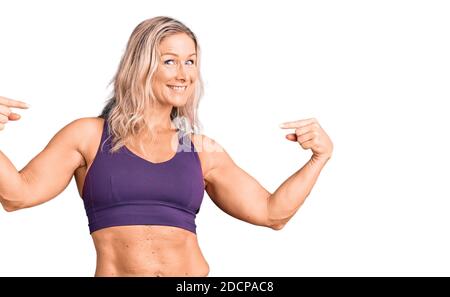 Middle age fit blonde woman wearing sportswear looking confident with smile on face, pointing oneself with fingers proud and happy. Stock Photo