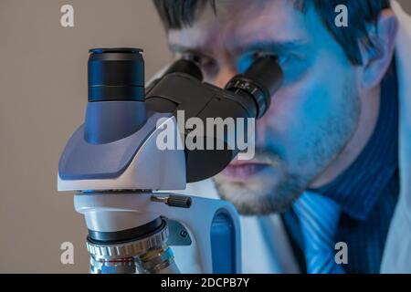 Young scientist is looking inside microscope in laboratory. Stock Photo