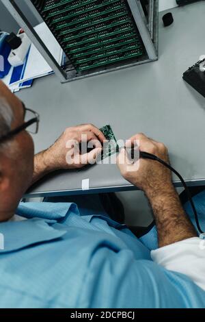 53/5000 man soldering on motherboard, motherboard bracket Stock Photo