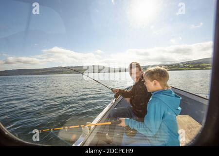 Through window side view of delighted father and son with rods fishing in sea on boat Stock Photo