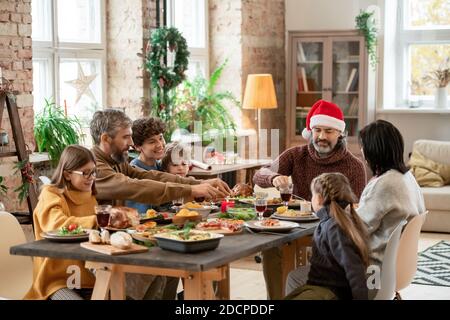 Happy multi-generation family sitting by served festive table on Christmas day Stock Photo