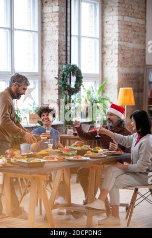 Two couples cheering up with flutes of champagne over festive table on xmas Stock Photo