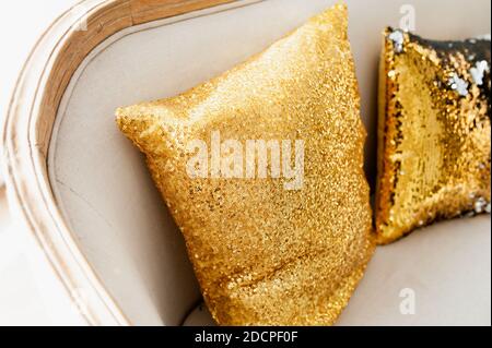 Gold shining decorative pillow with sequins on a beige sofa. Christmas decor for the home. Stock Photo