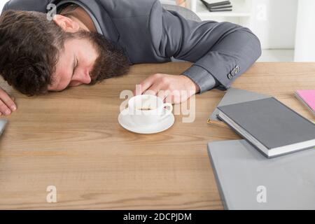 Tired businessman sleep in office. boss fell asleep on table. Man sleeping over workplace. coffee will help me. bored and exhausted guy sleep at work. need break for relax. being lazy. Stock Photo