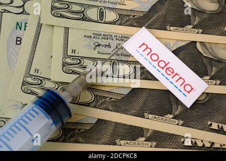 Stafford / United Kingdom - November 22 2020: Moderna vaccine Covid-19 concept. Syringe needle and sticker on it, blurred money on the background. Rea Stock Photo