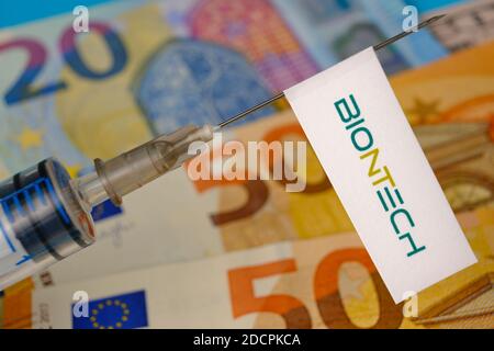 Stafford / United Kingdom - November 22 2020: BionTech vaccine Covid-19 concept. Syringe needle and sticker on it, blurred euros on the background. Re Stock Photo