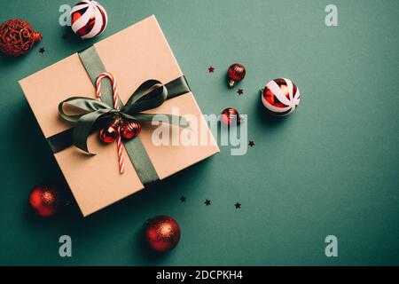 Vintage Christmas present and red balls on dark green background. Retro style Xmas gift box and decorations. Flat lay, top view. Stock Photo