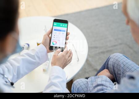 Doctor looking through results of individual health program of senior male Stock Photo